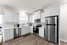A modern kitchen with white cabinets and stainless steel appliances.