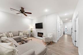 A living room with a grey couch, a grey armchair, a coffee table, a fireplace, and a television.