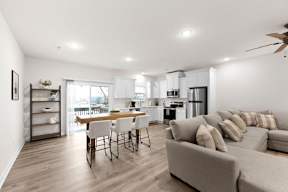 A modern living room with a dining area and kitchen in the background.
