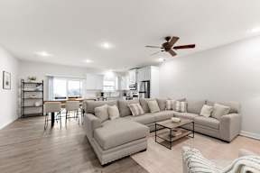A living room with a grey couch, a coffee table, and a ceiling fan.