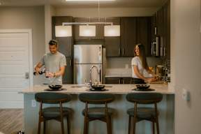 Two people are cooking in a modern kitchen.