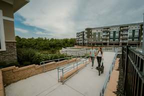 A man and a woman walking a dog on a patio.