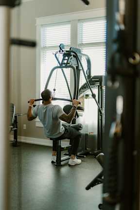 A man is working out on a cable machine in a gym.