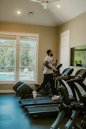 A man is running on a treadmill in a gym.