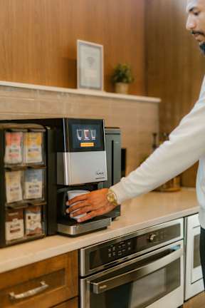 A man is reaching for a coffee pod in a coffee machine.