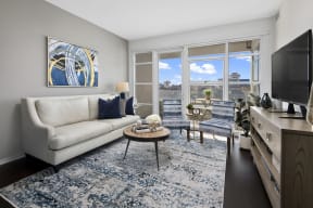 a living room with a white couch and a blue rug   and a window