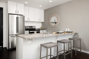 a kitchen with white cabinets and a counter top with three stools