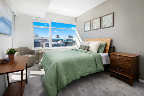 a bedroom with a large window and a green bed