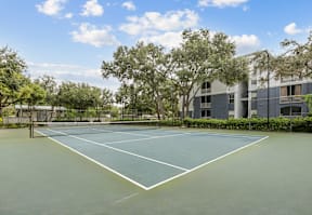 A tennis court surrounded by trees and a building.