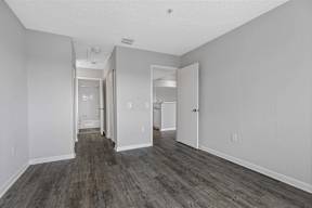 the living room of an apartment with white walls and wood flooring