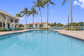 a large swimming pool with palm trees in front of a building