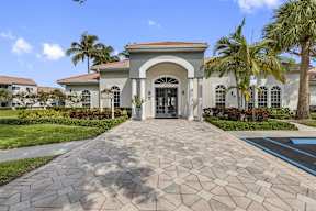 a house with a driveway and palm trees in front of it