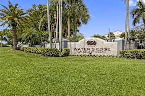 the waters edge at drew beach sign in front of palm trees