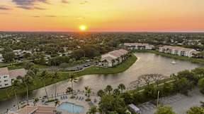 an aerial view of a resort with a lake at sunset