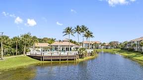 a house on the water with a pool and palm trees
