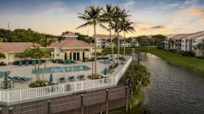 a large swimming pool in front of a house next to a canal