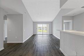 the living room and dining room of an apartment with wood flooring and a balcony