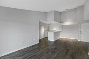 an empty living room and kitchen with white walls and wood floors