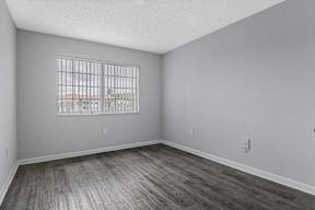 the spacious living room with wood flooring and a window