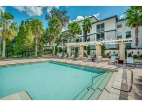 a swimming pool with palm trees and a building in the background