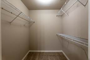 a spacious walk in closet with two shelves and a mirrored wall with two hanging racks