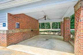 A covered patio area with a brick wall and a ceiling fan.