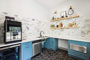 A kitchen with a stone backsplash and blue cabinets.