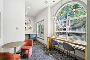 A kitchen with a table and chairs and a window with a view of trees.