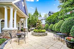 A patio with a table and chairs is surrounded by a garden.
