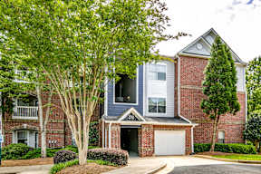 A two-story house with a garage and a tree in front.