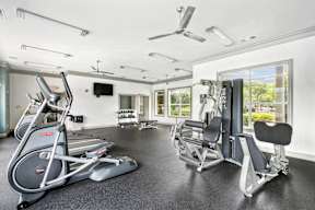 A spacious gym with a variety of equipment including treadmills, elliptical machines, and weight machines.