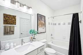 A white bathroom with a black shower curtain.
