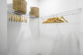 A white wall with a wire rack holding a yellow object and a woven basket.