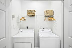 A white bathroom with two sinks and a washer and dryer.