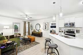 A modern kitchen with white cabinets and a green couch.