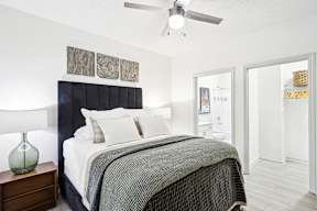 A bedroom with a bed, nightstand, and a ceiling fan.