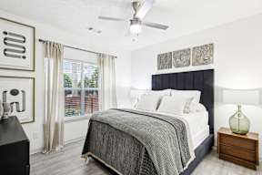 A bedroom with a bed, nightstand, and a ceiling fan.