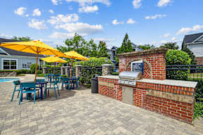 A patio with a brick oven and tables under yellow umbrellas.