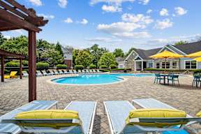 A pool surrounded by chairs and a pavilion.