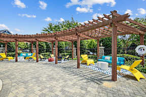 A wooden pergola with a blue couch and yellow chairs under it.