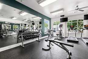 A gym with a variety of equipment including treadmills, weights, and exercise machines.