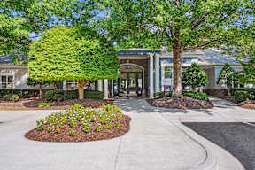 A building entrance with a large tree in front.