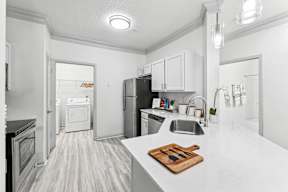 A kitchen with a white counter top and a wooden cutting board with knives on it.