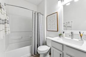 A white bathroom with a toilet, sink, and shower.