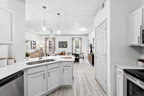 A kitchen with white cabinets and a wooden floor.