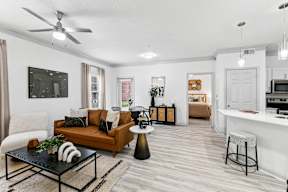 A living room with a brown sofa, a black coffee table, and a white chair.