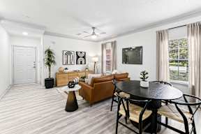 A living room with a brown couch, a black table, and a ceiling fan.