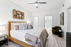 A bedroom with a bed, a chair, and a ceiling fan.