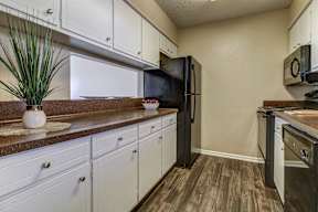 A kitchen with a black fridge and white cabinets.