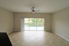 A room with a ceiling fan and sliding glass doors.